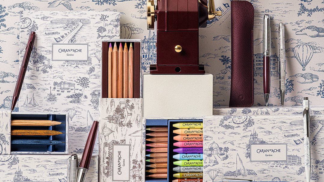 The Caran d'Ache Toile de Jouy collection in front of a wall with the Geneva motif